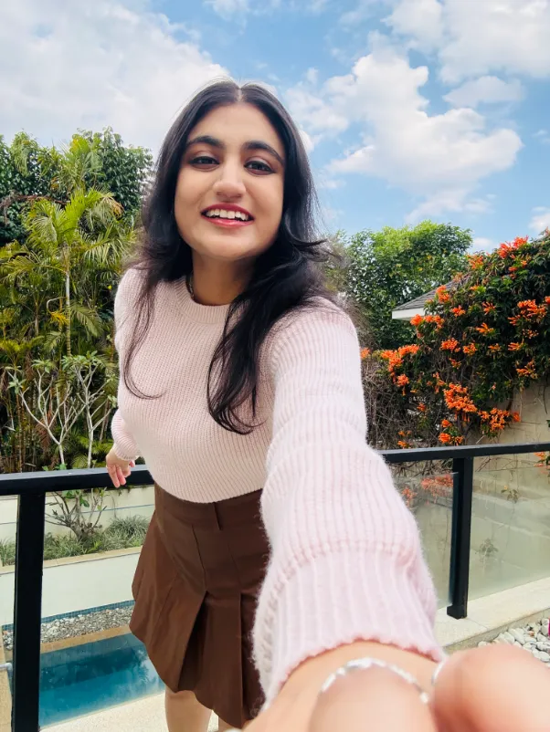 A selfie on a balcony against blue sky and trees.